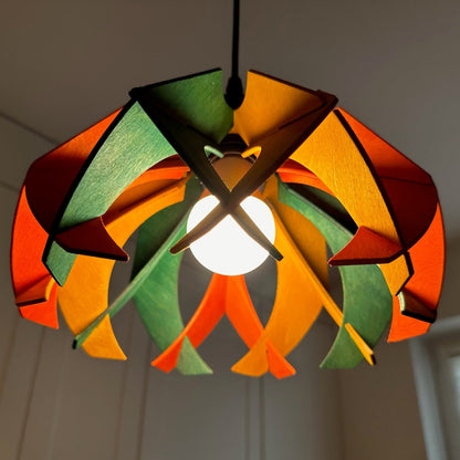 Close-up of a colorful small pendant lamp with green, yellow ochre, and scarlet stained wooden petals. The intricate design showcases the precision craftsmanship, with the light illuminating the vibrant colors beautifully.