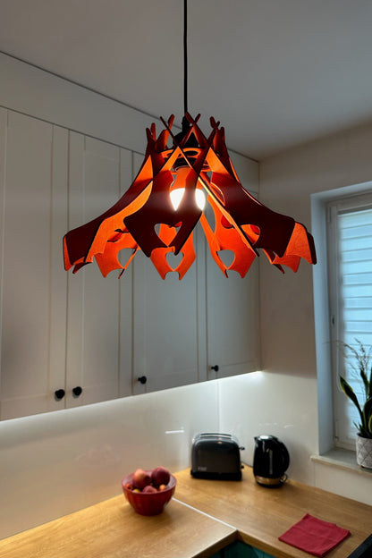 Red wooden pendant lampshade hanging in a modern kitchen with white cabinets and wooden countertops. The light fixture adds a vibrant, warm touch to the minimalist space.