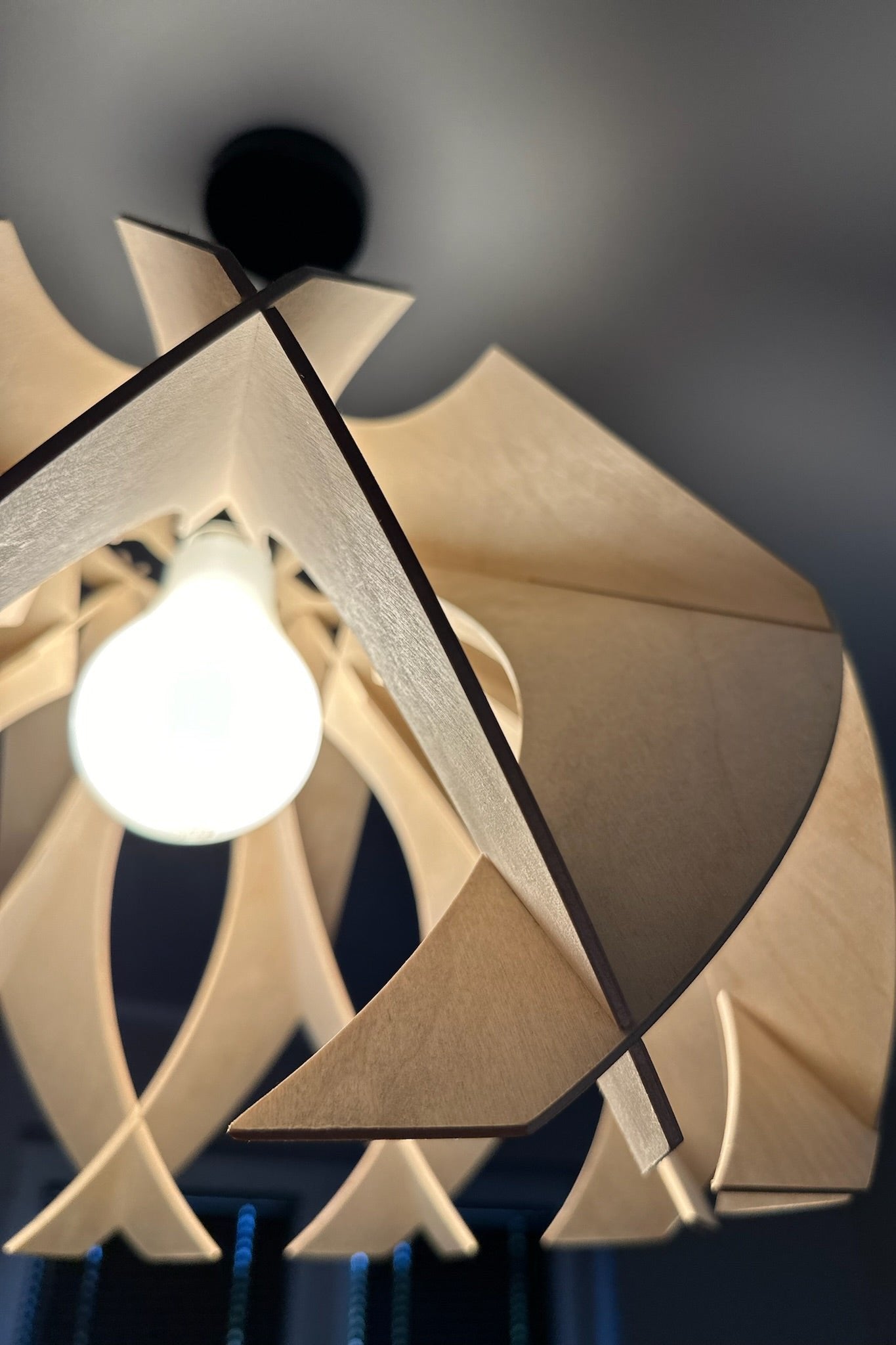 Detailed shot of the large wooden pendant lamp's petal-like curves, highlighting the natural birch wood grain and the modern, sculptural design.