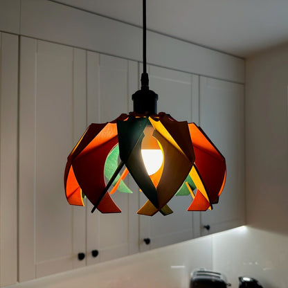 Colorful small pendant lamp with green, yellow ochre, and scarlet stained wooden petals, hanging in a cozy kitchen. The light creates a warm and lively atmosphere, perfect for brightening up small spaces.